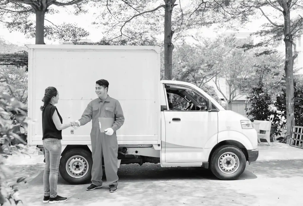 Smiling delivery couriers carrying cardboard boxes for customer shipment