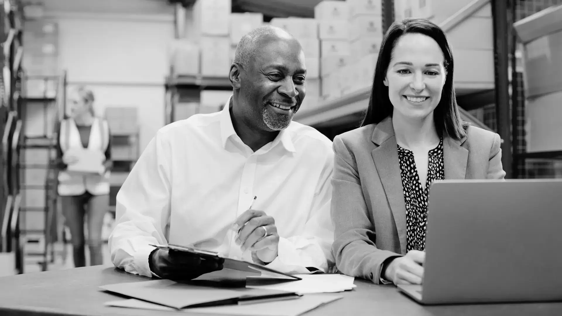 Older man and woman smiling while reviewing documents at a logistics planning desk