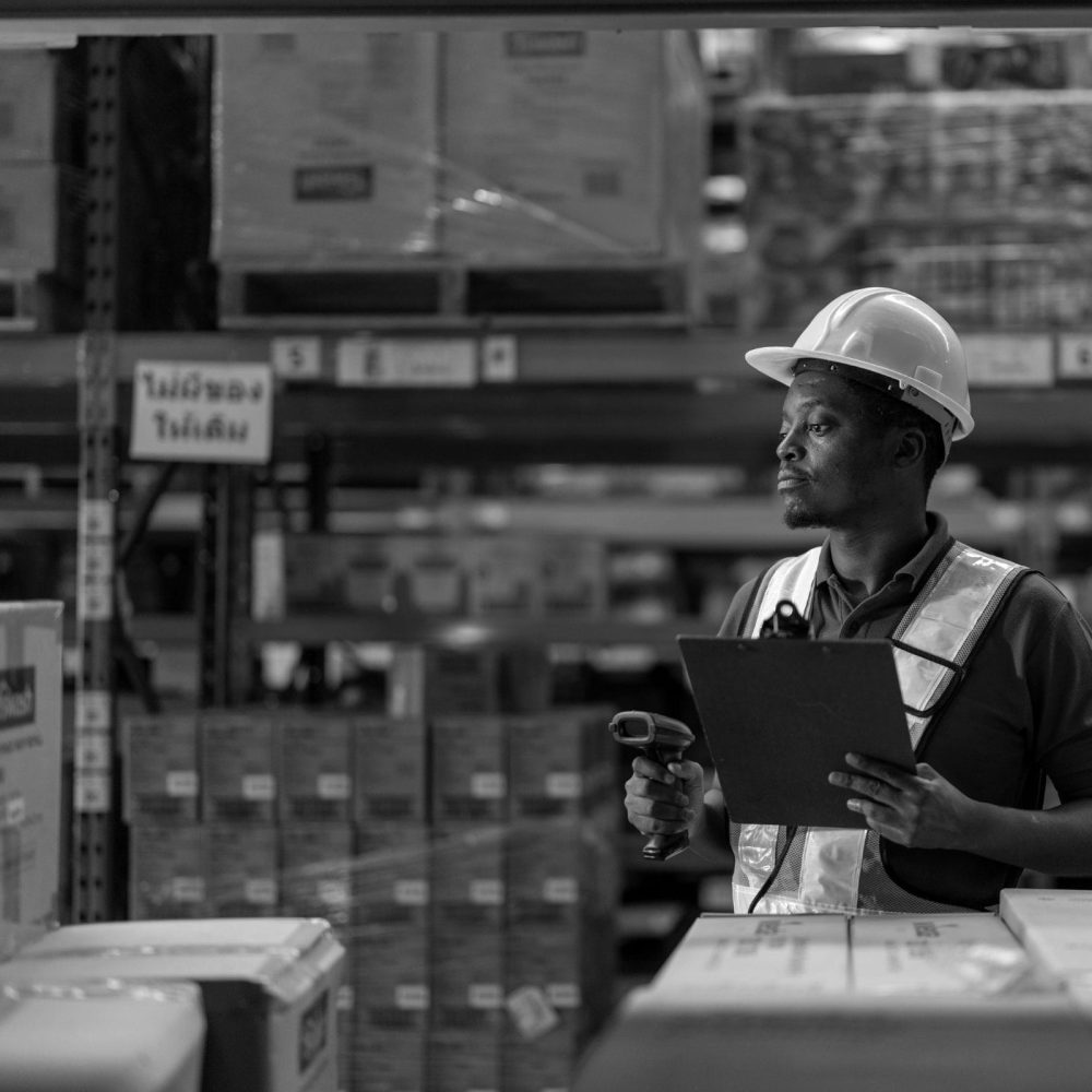 Warehouse supervisor in hard hat reviewing clipboard while standing in fulfillment area
