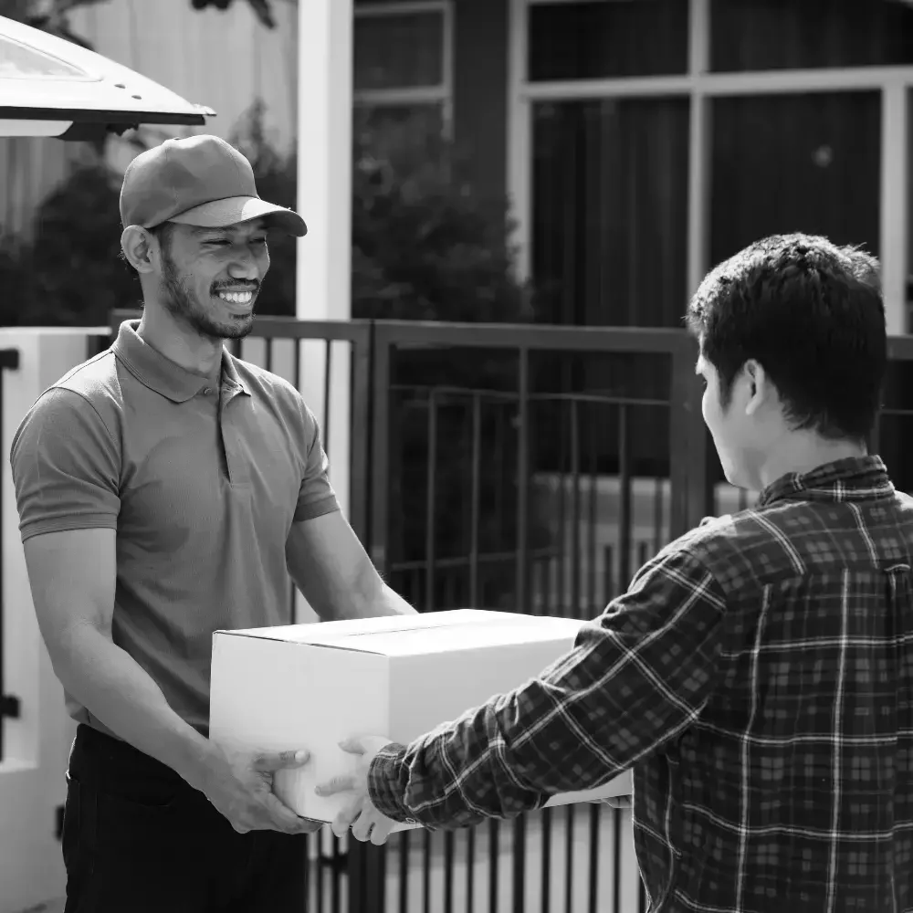 Warehouse team member handing over packed box to smiling customer at loading dock