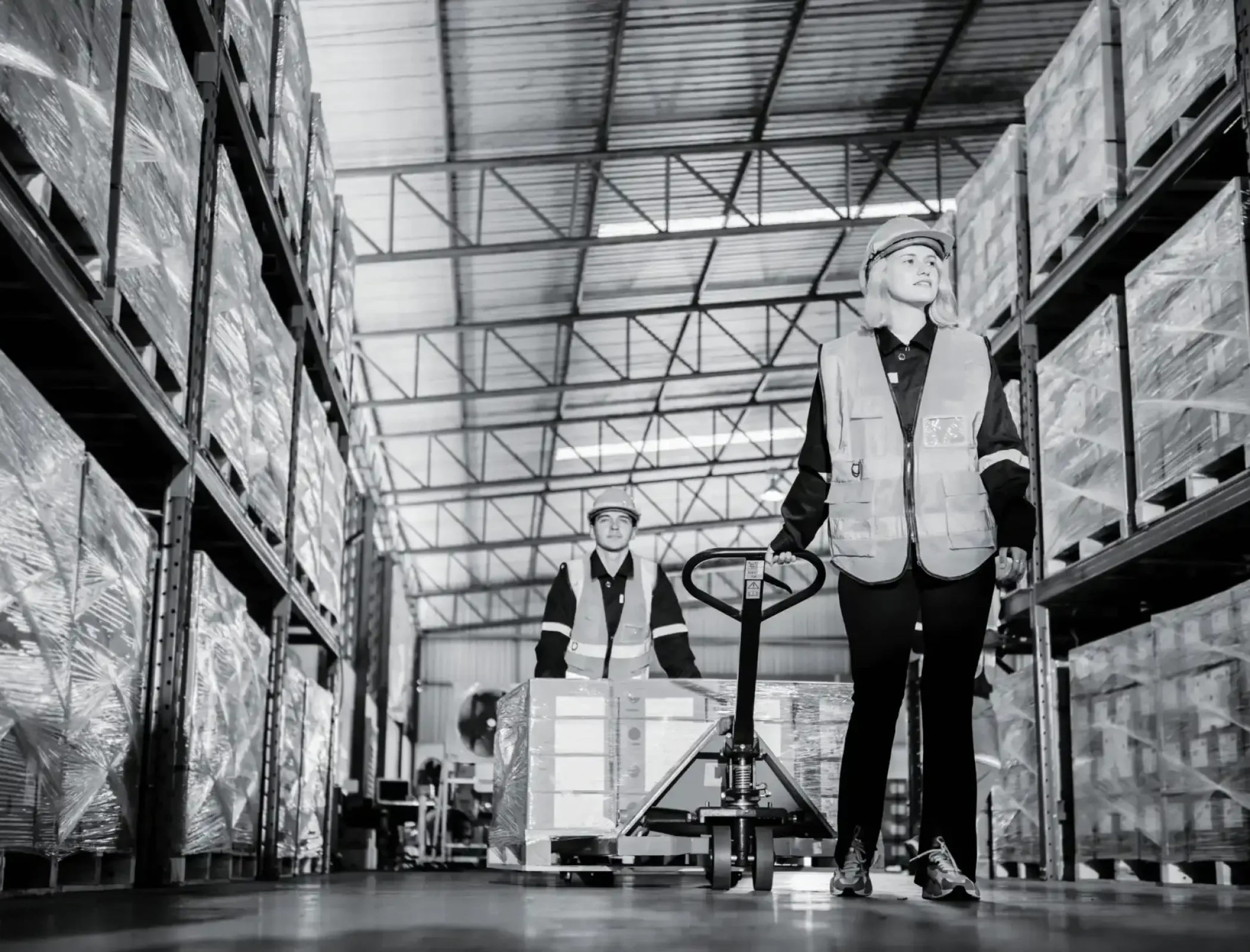 Warehouse operator standing on an electric pallet jack in a fulfillment center